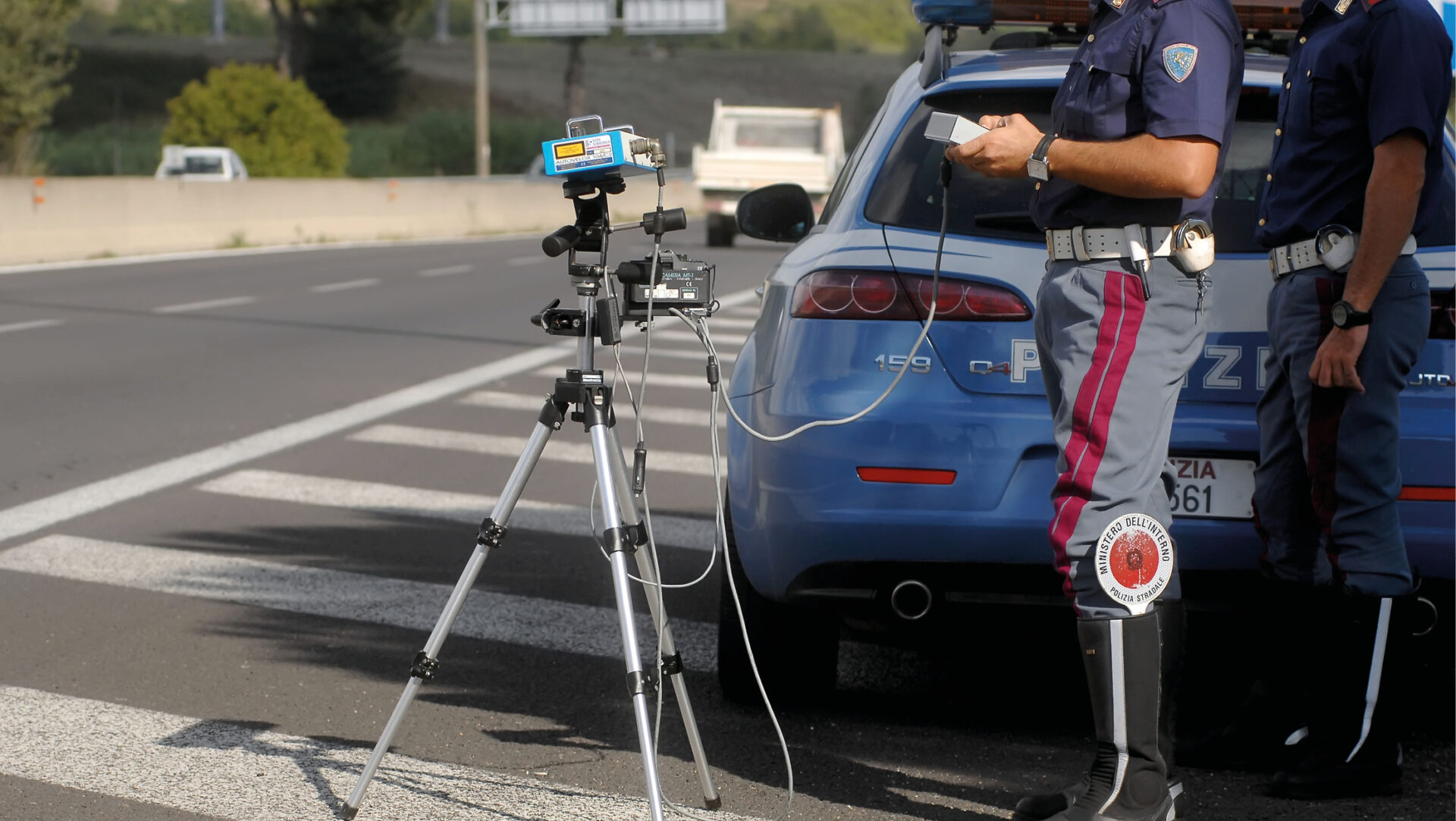 Polizia Stradale utilizza un autovelox su strada trafficata per il controllo della velocità.