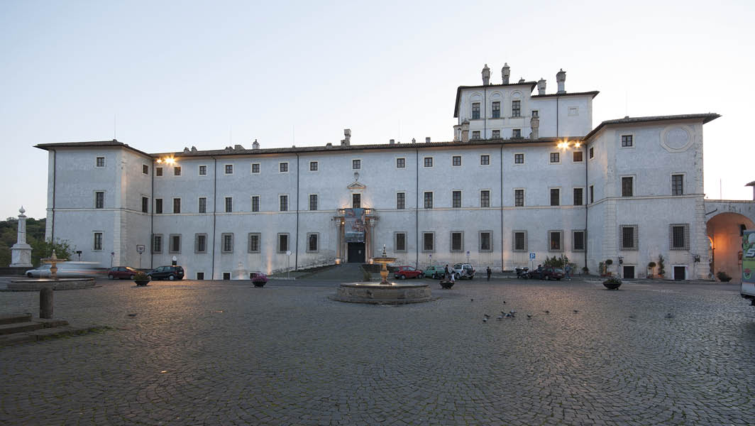 Palazzo Chigi ad Ariccia illuminato al tramonto, con piazza antistante e fontana centrale