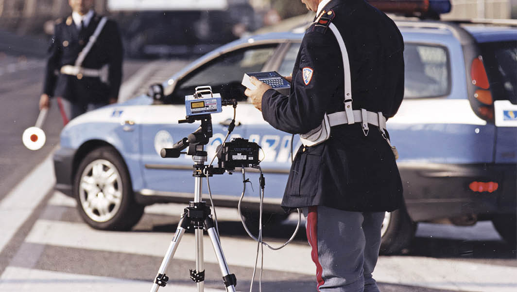 Agenti della Polizia di Stato durante il controllo della velocità con autovelox mobile su strada.