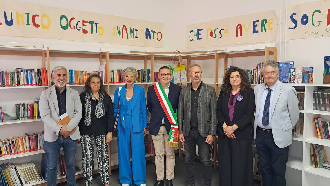 Gruppo di rappresentanti dell'amministrazione comunale e della scuola riuniti davanti a scaffali di libri per l'inaugurazione di una nuova biblioteca scolastica presso l'I.C. Giovanni Falcone di Grottaferrata.