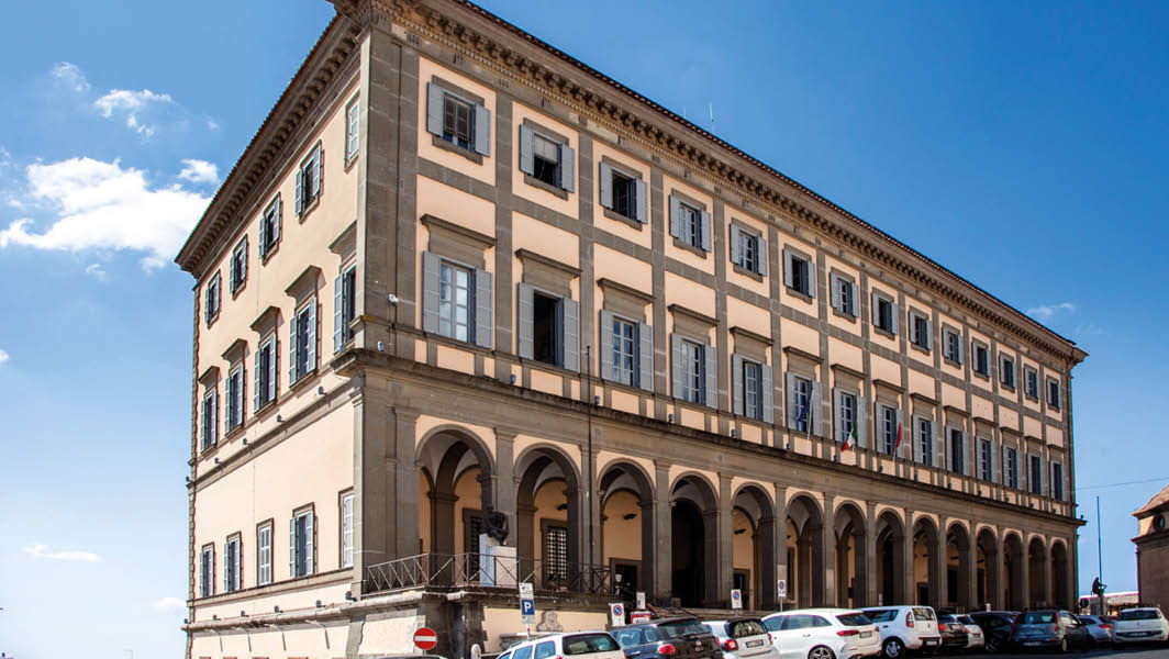 Facciata del Palazzo Comunale di Velletri con cielo azzurro e auto parcheggiate davanti.