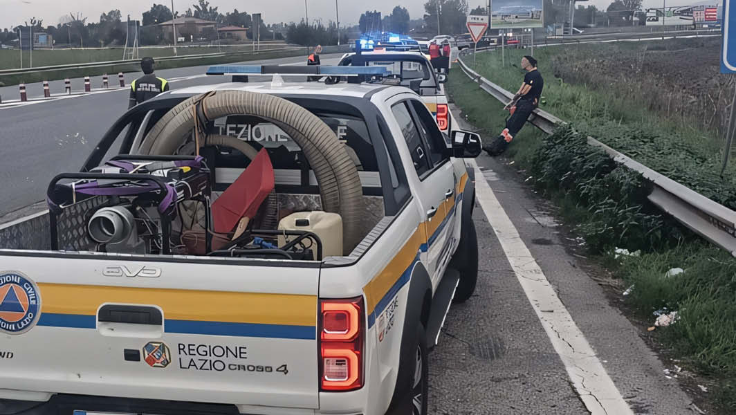 I volontari della Protezione Civile di Albano Laziale in azione durante l'emergenza alluvione in Emilia Romagna, con veicoli di supporto parcheggiati lungo una strada mentre operano sul posto.