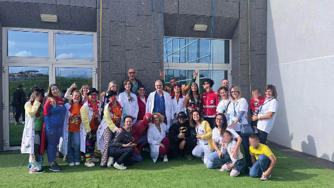 Gruppo di supereroi acrobati, clown, operatori sanitari e volontari riuniti davanti all’Ospedale dei Castelli dopo un evento per i piccoli pazienti.