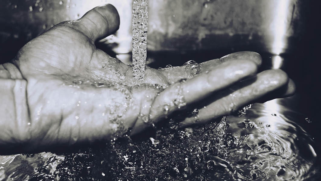 Primo piano di una mano sotto un getto d'acqua, rappresentazione simbolica della risorsa idrica nel Comune di Marino.