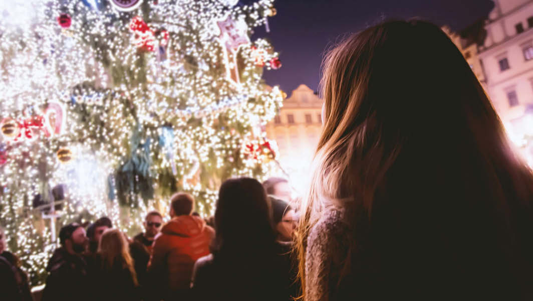 Persone osservano un grande albero di Natale illuminato con decorazioni brillanti, a Santa Maria delle Mole.