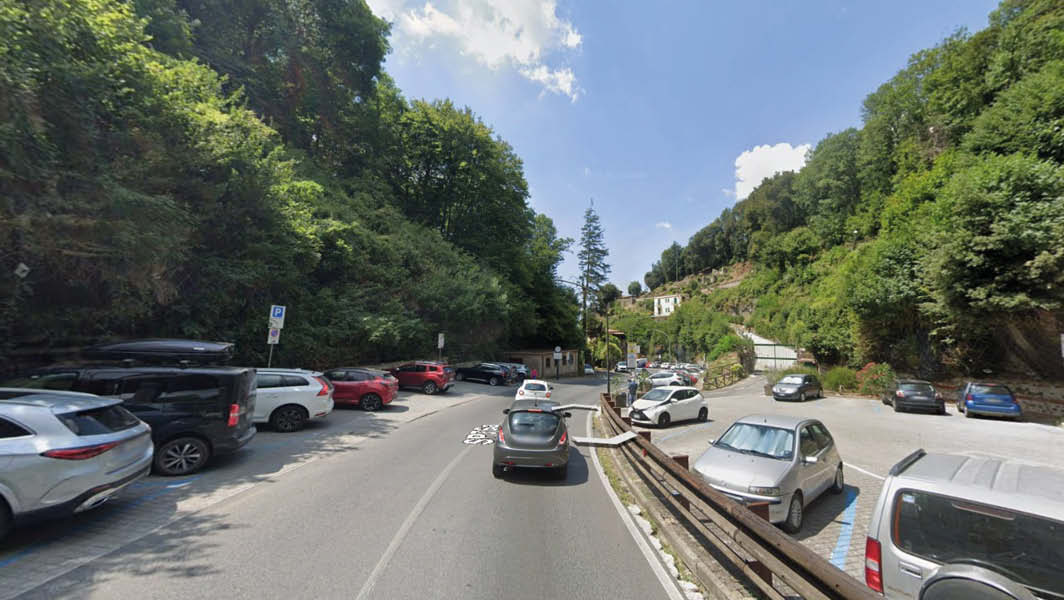 veduta di via Riccardo De Sanctis a Nemi con parcheggi laterali e traffico veicolare, circondata da verde e colline