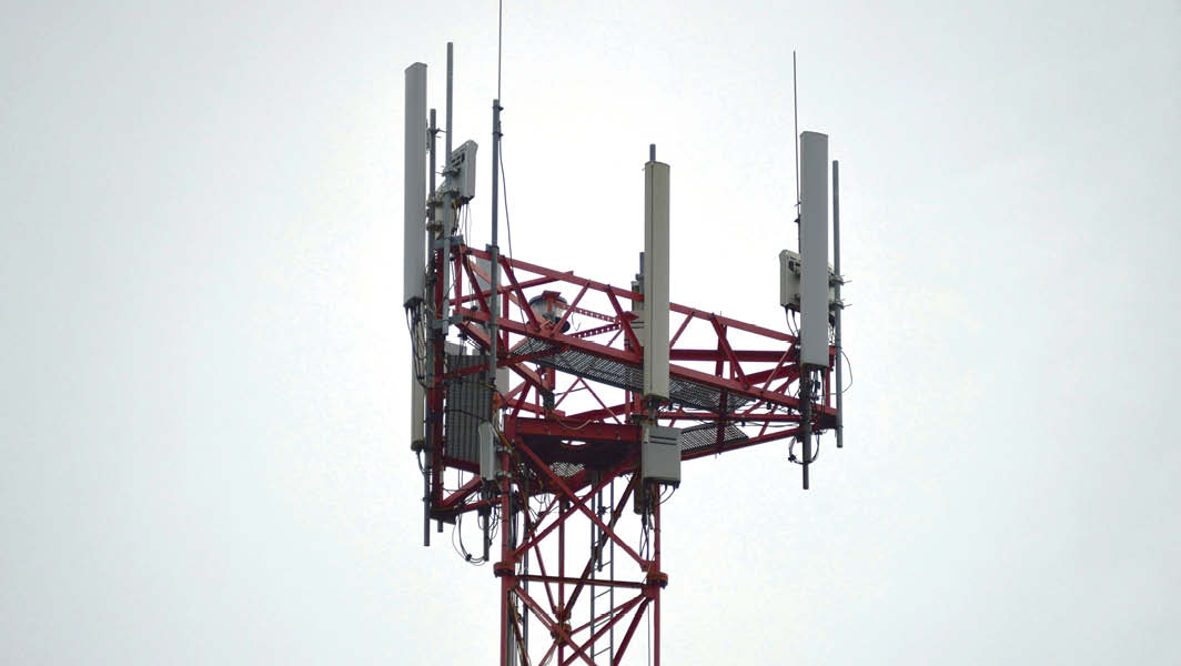 Antenna di telecomunicazione a Marino su una struttura rossa con pannelli e cavi visibili contro un cielo grigio.