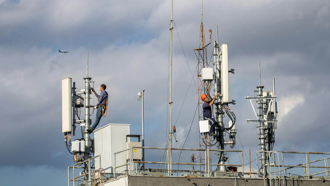 Tecnici al lavoro su antenne di telecomunicazione su un tetto con cielo nuvoloso, ad Albano Laziale.