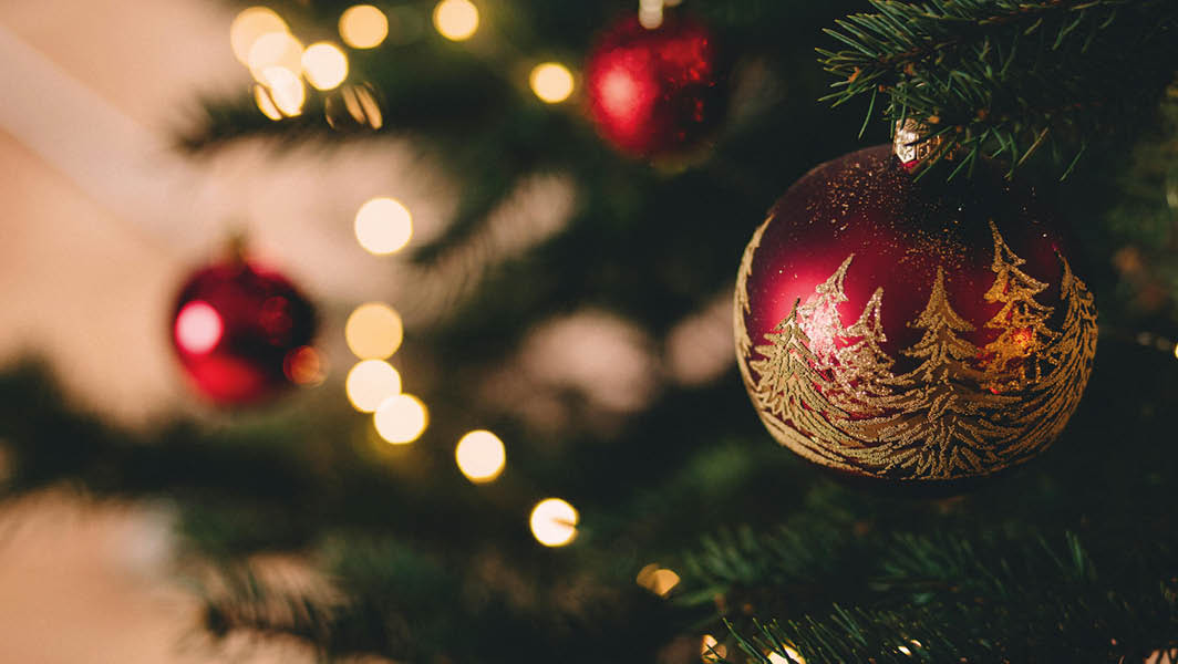 Decorazione natalizia con pallina rossa e alberi dorati su un albero di Natale illuminato a Ciampino.