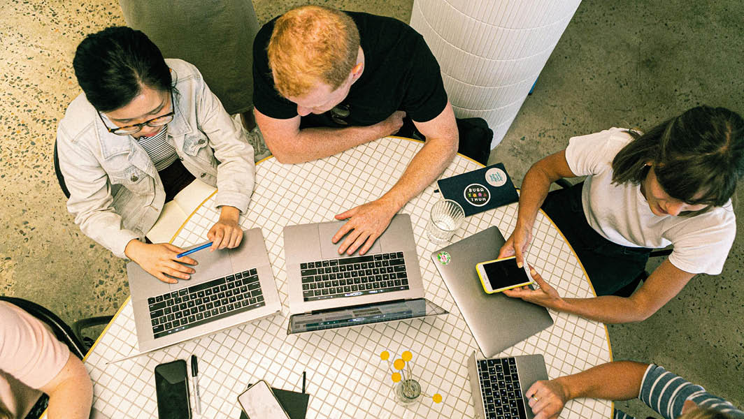 Un gruppo di persone lavora insieme attorno a un tavolo, in un ambiente simile a quello delle Officine Municipali di Velletri.