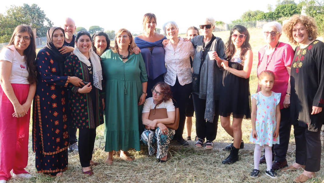 Un gruppo di persone, tra cui donne di diverse culture e una bambina, posa sorridendo all’aperto durante un evento di Raggio Verde.