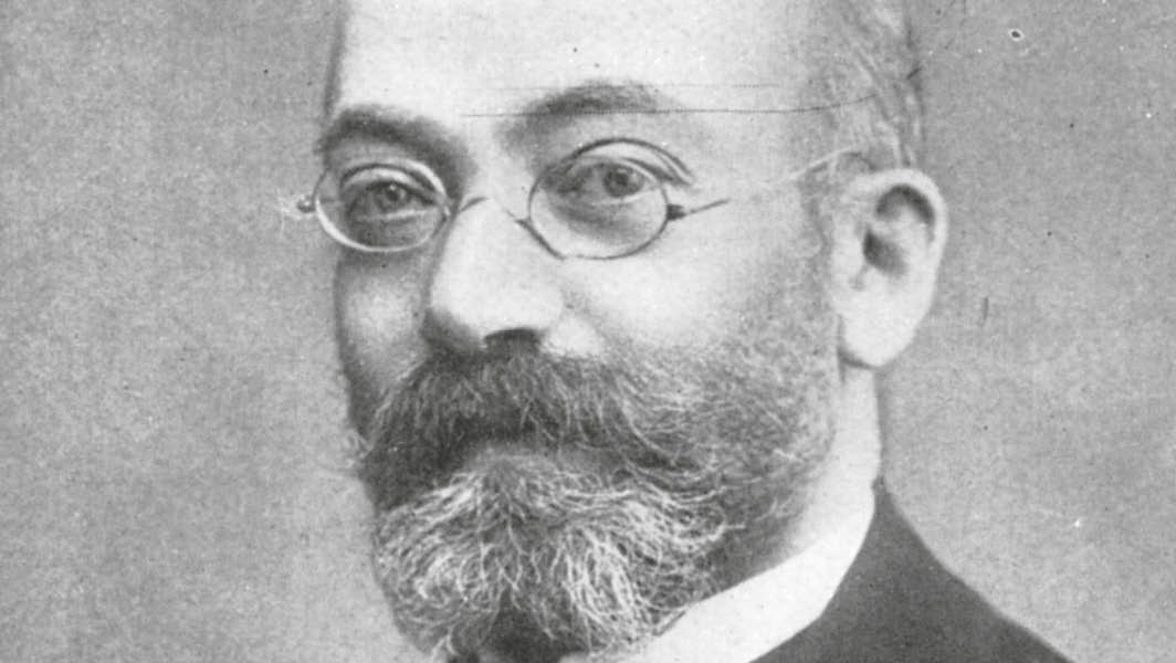 Ritratto di Ludwik L. Zamenhof, medico e linguista polacco, creatore dell’esperanto, con barba folta, occhiali tondi e abito formale.